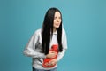 Woman using hot water bottle to relieve abdominal pain on light blue background Royalty Free Stock Photo