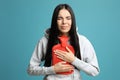 Woman using hot water bottle to relieve pain on light blue background Royalty Free Stock Photo