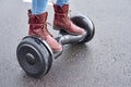 Close up of woman using hoverboard on asphalt road. Feet on electrical scooter outdoor Royalty Free Stock Photo