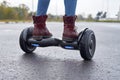 Close up of woman using hoverboard on asphalt road. Feet on electrical scooter outdoor