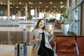 Woman using internet by tablet in airport hall near valise and showing thumbs up. Royalty Free Stock Photo