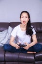 Woman using joystick controller playing video game on sofa in li