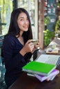 Woman using laptop at cafe while drinking coffee Royalty Free Stock Photo