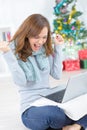 Woman using laptop at christmas making gesture triumph