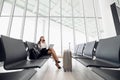 Woman using laptop computer at airport terminal sitting with luggage suitcase for business travel waiting flight Royalty Free Stock Photo