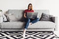 Woman using laptop computer sitting on sofa in living room