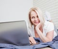 Woman using laptop in home bedroom. Guy lying on bed and typing with notebook computer. Person in the morning with Royalty Free Stock Photo