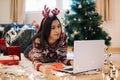 Woman using laptop while lying on floor with tree and presents Royalty Free Stock Photo