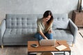 Woman using laptop and mobile phone on sofa. Royalty Free Stock Photo