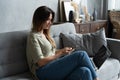 Woman using laptop and mobile phone on sofa. Royalty Free Stock Photo