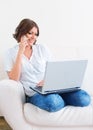 Woman using laptop and a phone on the sofa Royalty Free Stock Photo