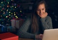 Woman using laptop, shopping online. Christmas tree in the background