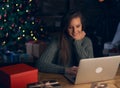 Woman using laptop, shopping online, using credit card at home. Christmas tree in the background Royalty Free Stock Photo