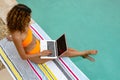 Woman using laptop while sitting at the edge of swimming pool Royalty Free Stock Photo