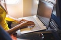 Woman using laptop while is sitting in plane near window. Royalty Free Stock Photo