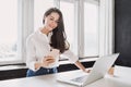 Woman using laptop and smartphone in office. Beautiful girl working at home.