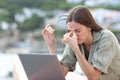 Woman using laptop suffering eyestrain in a balcony Royalty Free Stock Photo