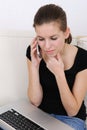 Woman using a laptop and talking on phone Royalty Free Stock Photo