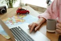 Woman using laptop to plan trip at wooden table