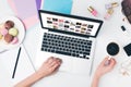 top view of woman drinking coffee with macaroon while using laptop