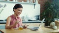 Woman using laptop for video call online. Girl pouring honey into cup of tea. Royalty Free Stock Photo