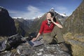 Woman Using Laptop And Walkie Talkie Against Mountains