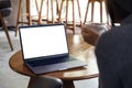 A woman using and looking at laptop with blank white desktop screen while drinking hot coffee in cafe Royalty Free Stock Photo