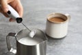 Woman using milk frother in pitcher near cup Royalty Free Stock Photo