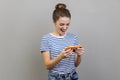 Woman using mobile phone with attentive focused expression, playing video game on cellphone. Royalty Free Stock Photo
