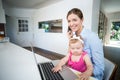 Woman using mobile phone with baby girl by laptop Royalty Free Stock Photo