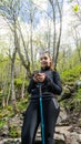 Woman using mobile phone in forest. Happy young girl walking in the forest and using her modern cell phone, taking pictures of the