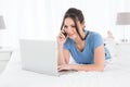 Woman using mobile phone and laptop in bed Royalty Free Stock Photo