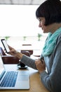 Woman using mobile phone with laptop on table Royalty Free Stock Photo