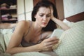 Woman using mobile phone while man sleeping on bed Royalty Free Stock Photo