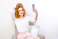 Woman using mobile phone for Online video chat on white. Joyful woman holding mobile phone smiling on camera while taking selfie, Royalty Free Stock Photo