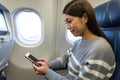 Woman using mobile phone in plane cabin Royalty Free Stock Photo