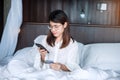 Woman using mobile smart phone and credit card for online shopping while making order on bed in morning at home. technology, Royalty Free Stock Photo