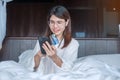 Woman using mobile smart phone and credit card for online shopping while making order on bed in morning at home. technology, Royalty Free Stock Photo