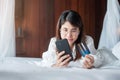 Woman using mobile smart phone and credit card for online shopping while making order on bed in morning at home. technology, Royalty Free Stock Photo