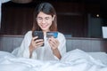 Woman using mobile smart phone and credit card for online shopping while making order on bed in morning at home. technology, Royalty Free Stock Photo