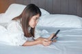 Woman using mobile smart phone and credit card for online shopping while making order on bed in morning at home. technology, Royalty Free Stock Photo