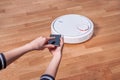 Woman using mobile to control robotic vacuum cleaner Royalty Free Stock Photo