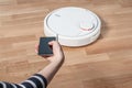 Woman using mobile to control robotic vacuum cleaner Royalty Free Stock Photo