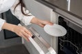 Woman using modern built-in dishwasher machine in kitchen Royalty Free Stock Photo