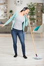 woman using mop as micophone and singing while doing housework Royalty Free Stock Photo