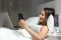 Woman using multiple devices in the night on the bed