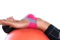 Woman using orange fitness ball to strech her back and exercise her abs isolated on white background