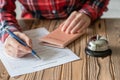 Woman using passport filling hotel reservation form in the hotel. Silver vintage bell on wooden rustic reception desk. Hotel Royalty Free Stock Photo