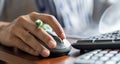 Woman using PC mouse while working on computer at table. Close up on hand of young woman sitting at wooden table Royalty Free Stock Photo