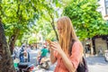 Woman using phone app for taxi ride hailing service or reading travel guide. Girl tourist searching for map directions